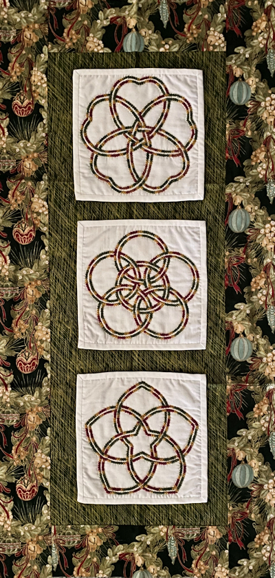 San Kamon knots as small quilts on a tablerunner for a Christmas theme.